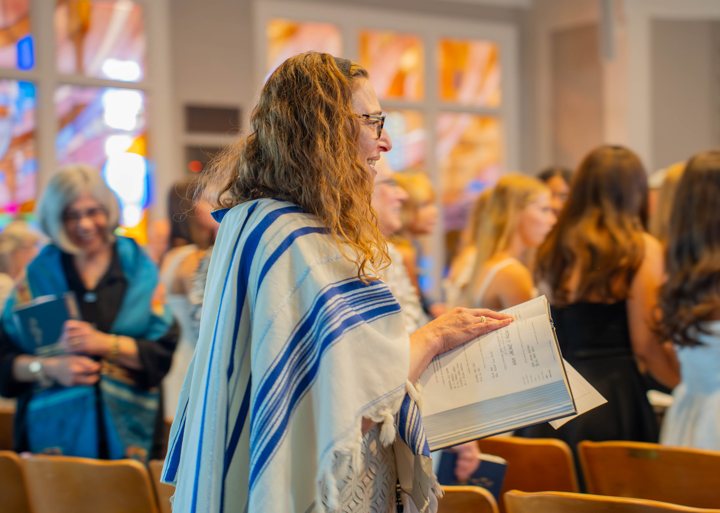 A smiling participant holds an open prayer book during a ceremony.